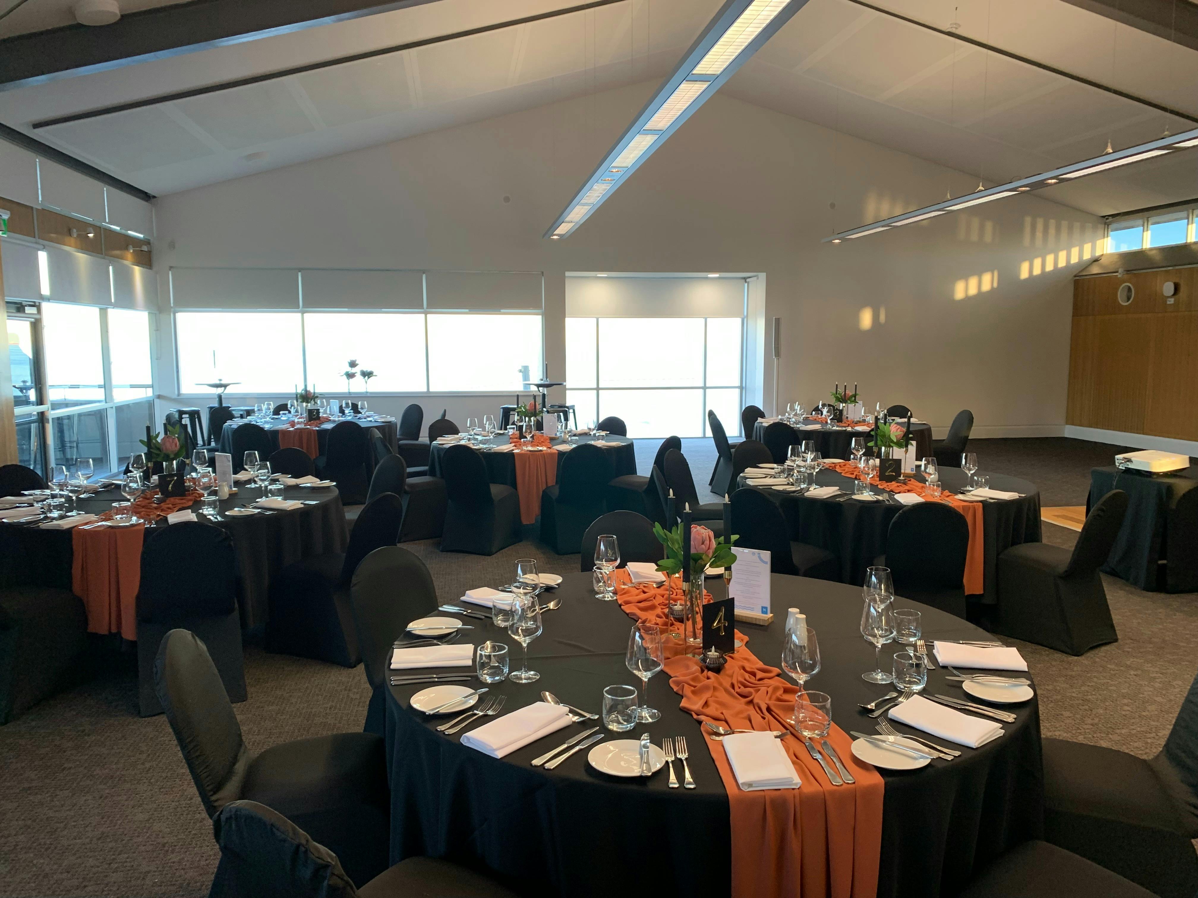 Inside Fort Scratchley Function Centre with round tables set for dinner with black table cloths