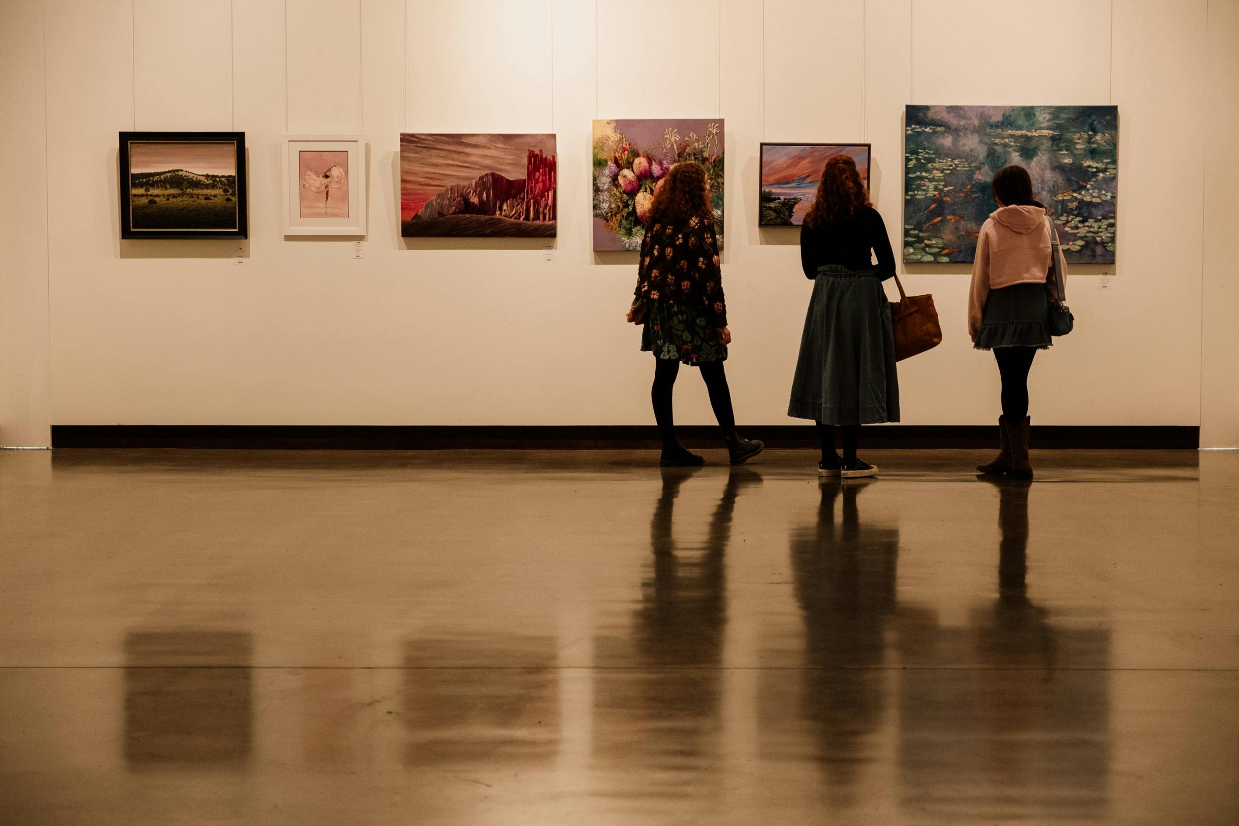 Three people standing in front of art in gallery