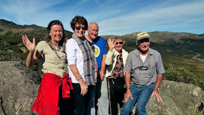 Four seniors and tour guide at Charlotte pass lookout with Mount Kosciuszko behind