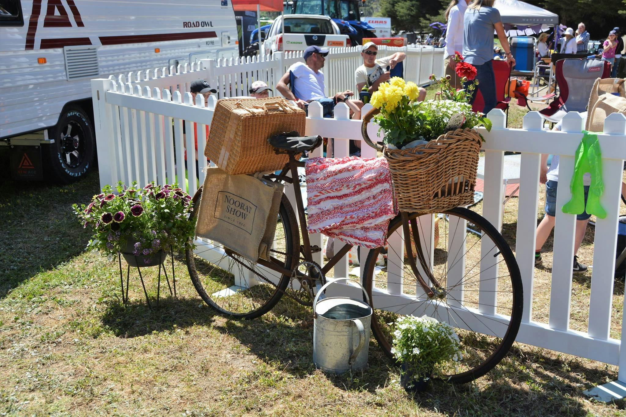 Decorative bicycle leaning on a white picket fence
