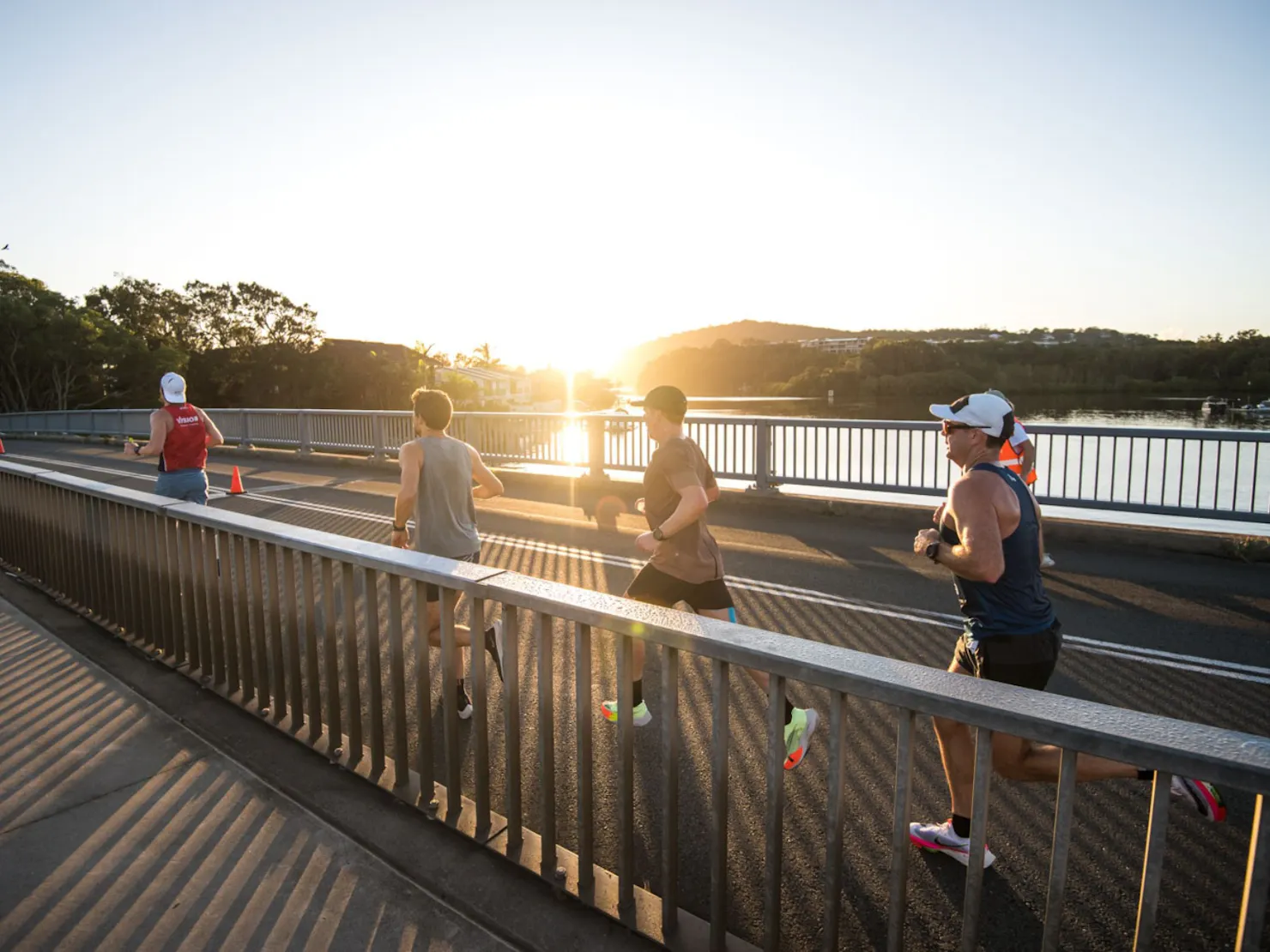 Runners running across the bridge into the sun