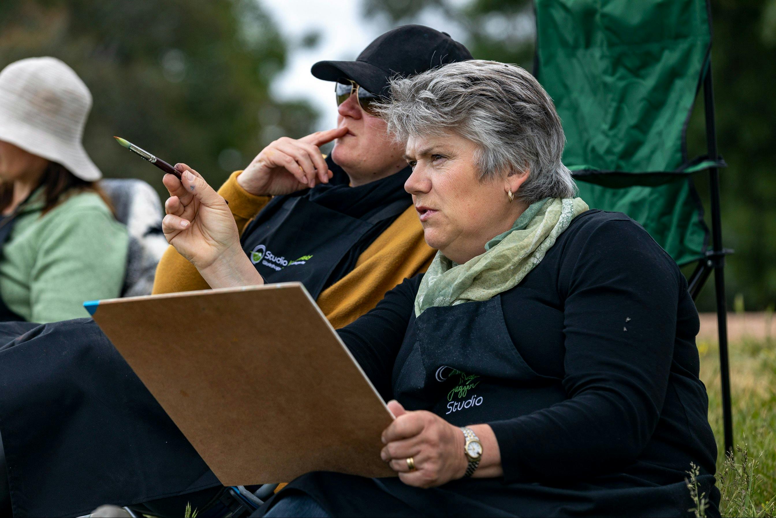 a teacher explaining composition to a student, painting outdoors.