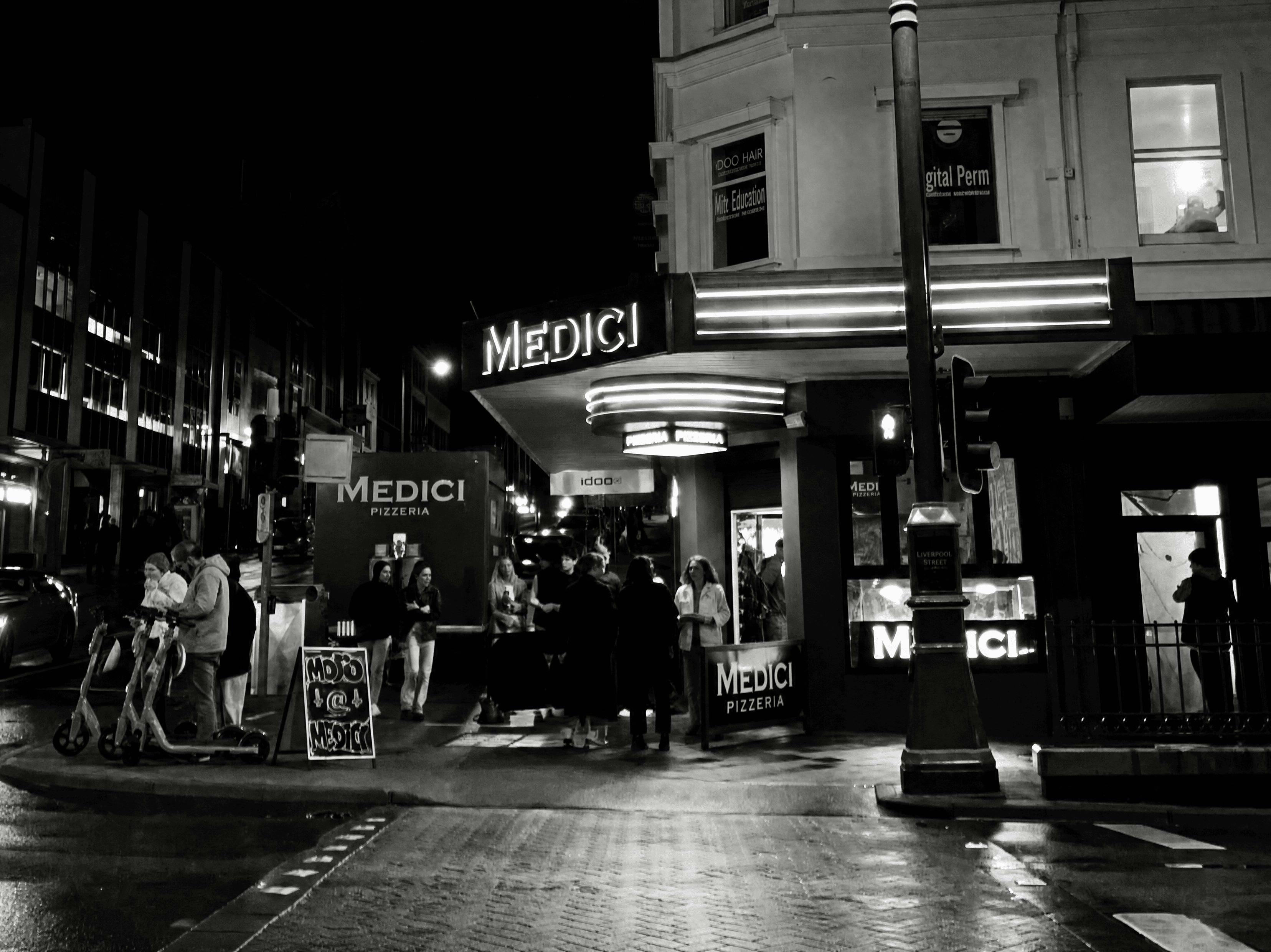 Medici Pizzeria shopfront lit up at night on a  street corner in central Hobart