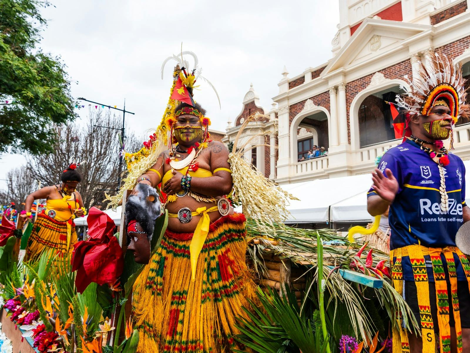 Men and women in traditional Papua New Guinea outfits stand on a parade float