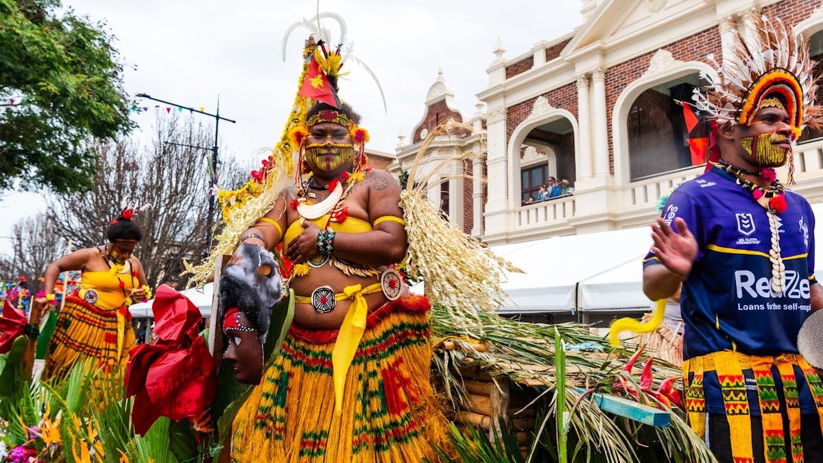 Men and women in traditional Papua New Guinea outfits stand on a parade float
