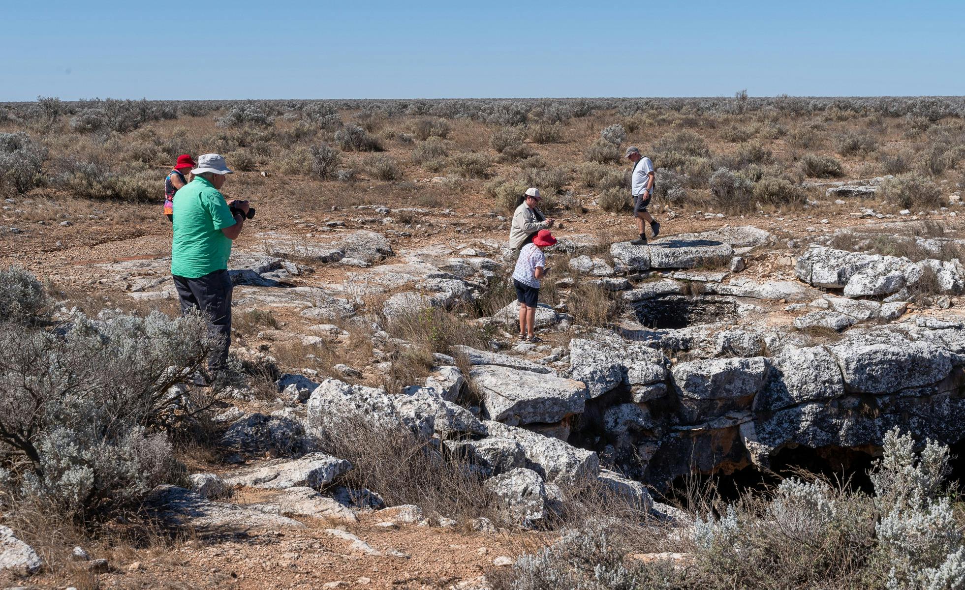 People walking around a caves rim