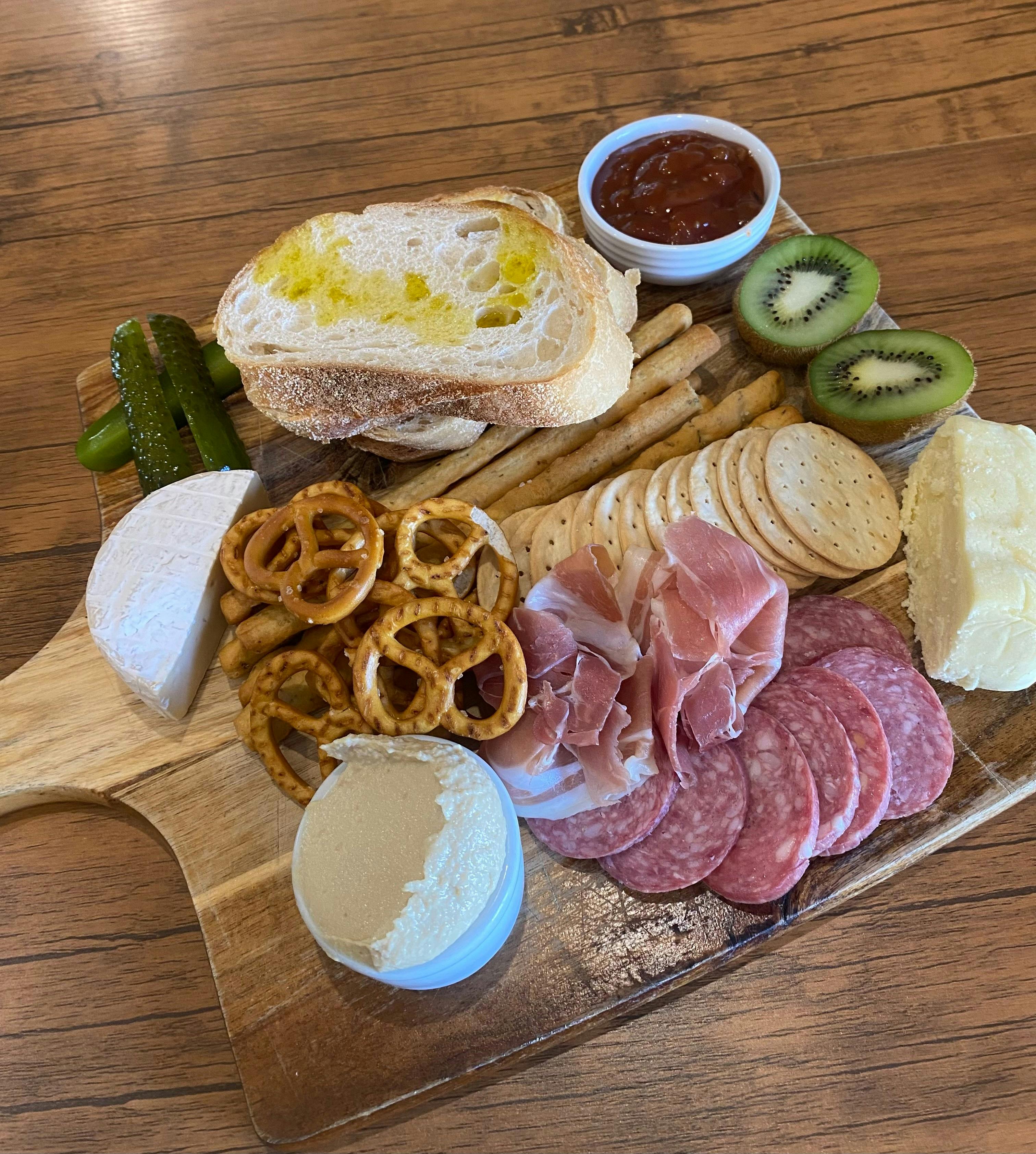 A charcuterie board, with assorted bread, meat, cheese, pretzels