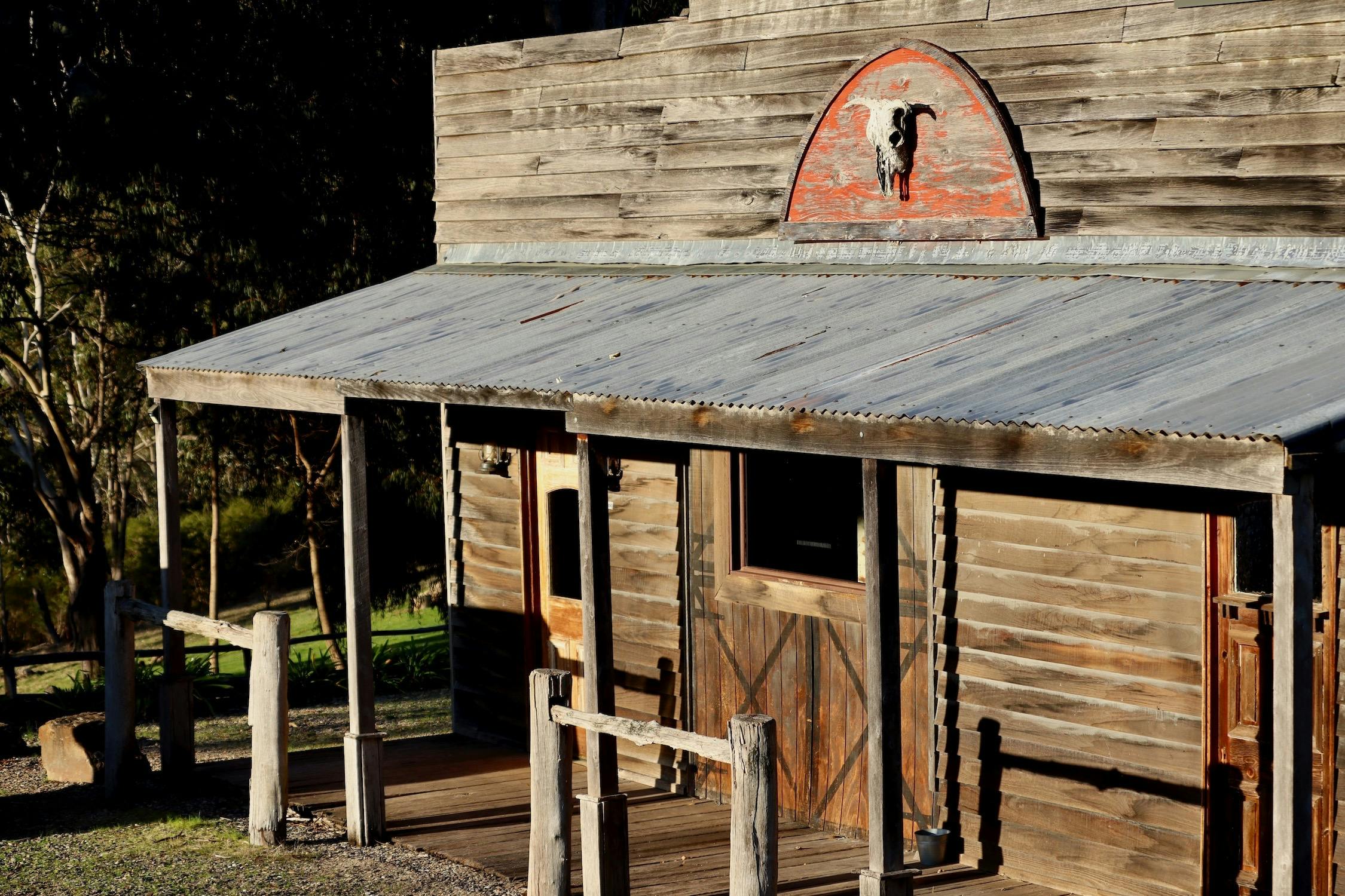 A timber building with a verandah in a rustic style with two hitching posts out front