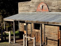 A timber building with a verandah in a rustic style with two hitching posts out front