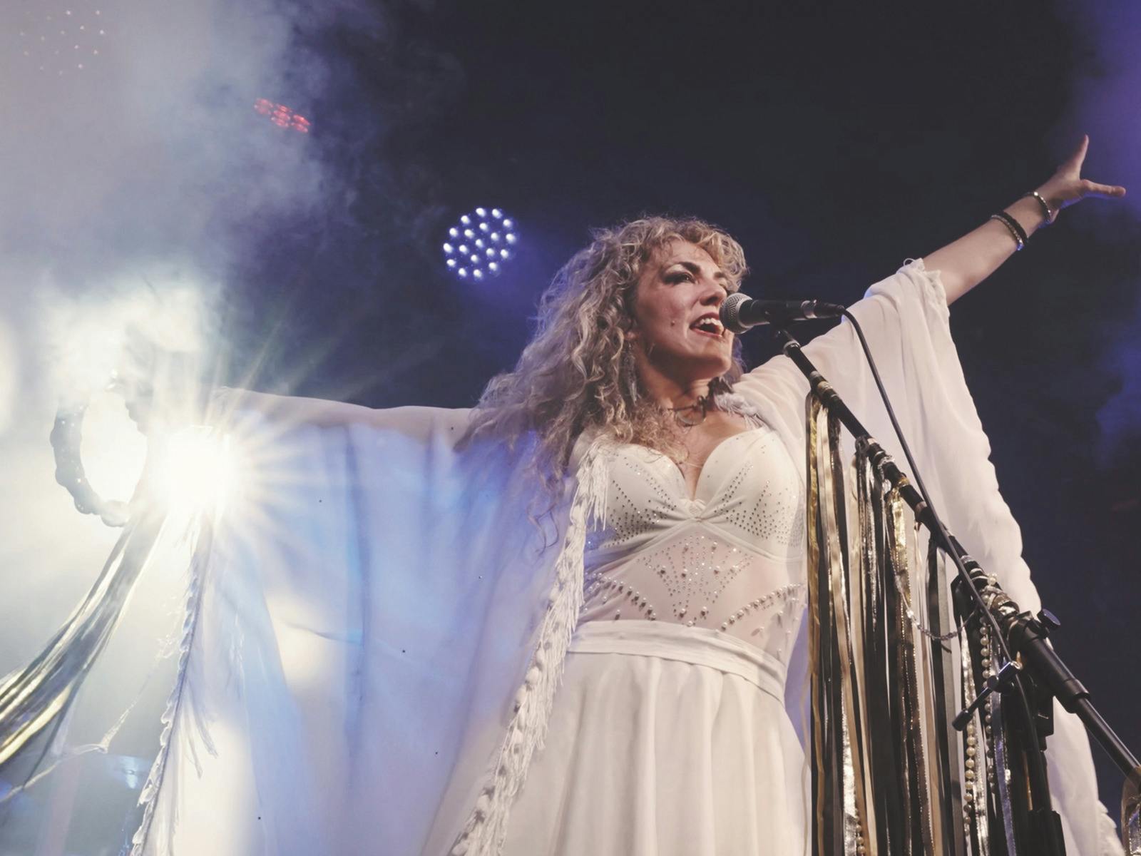Woman on stage with white dress singing white dress