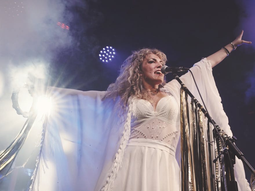 Woman on stage with white dress singing white dress