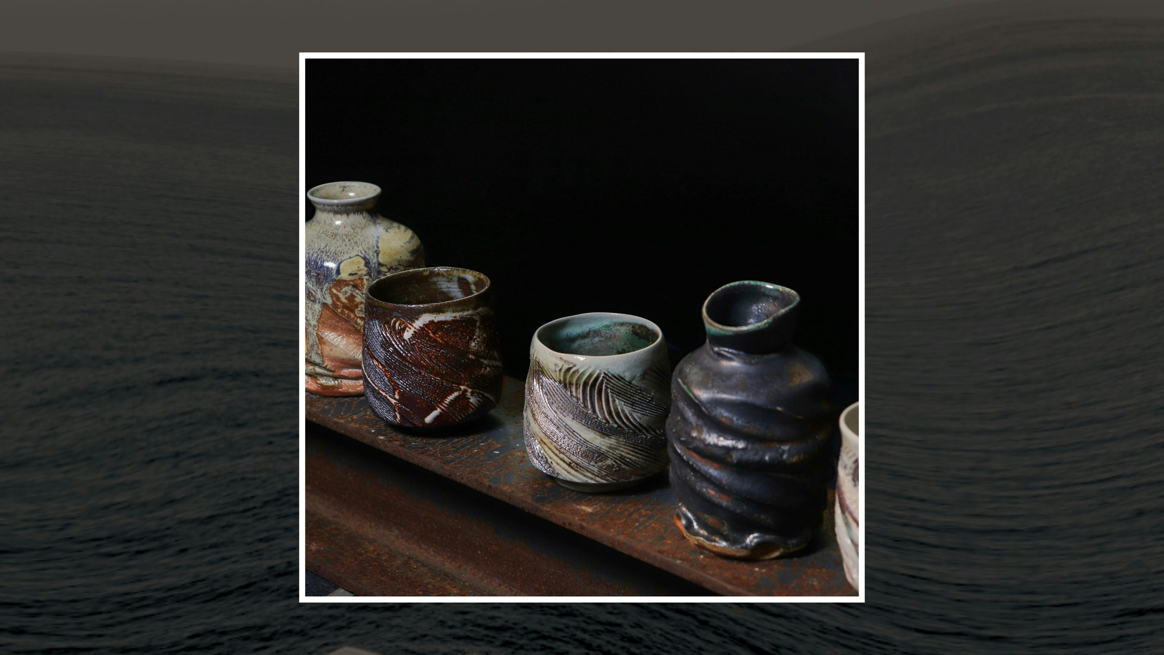 A series of ceramics in a row, dark browns and patterns