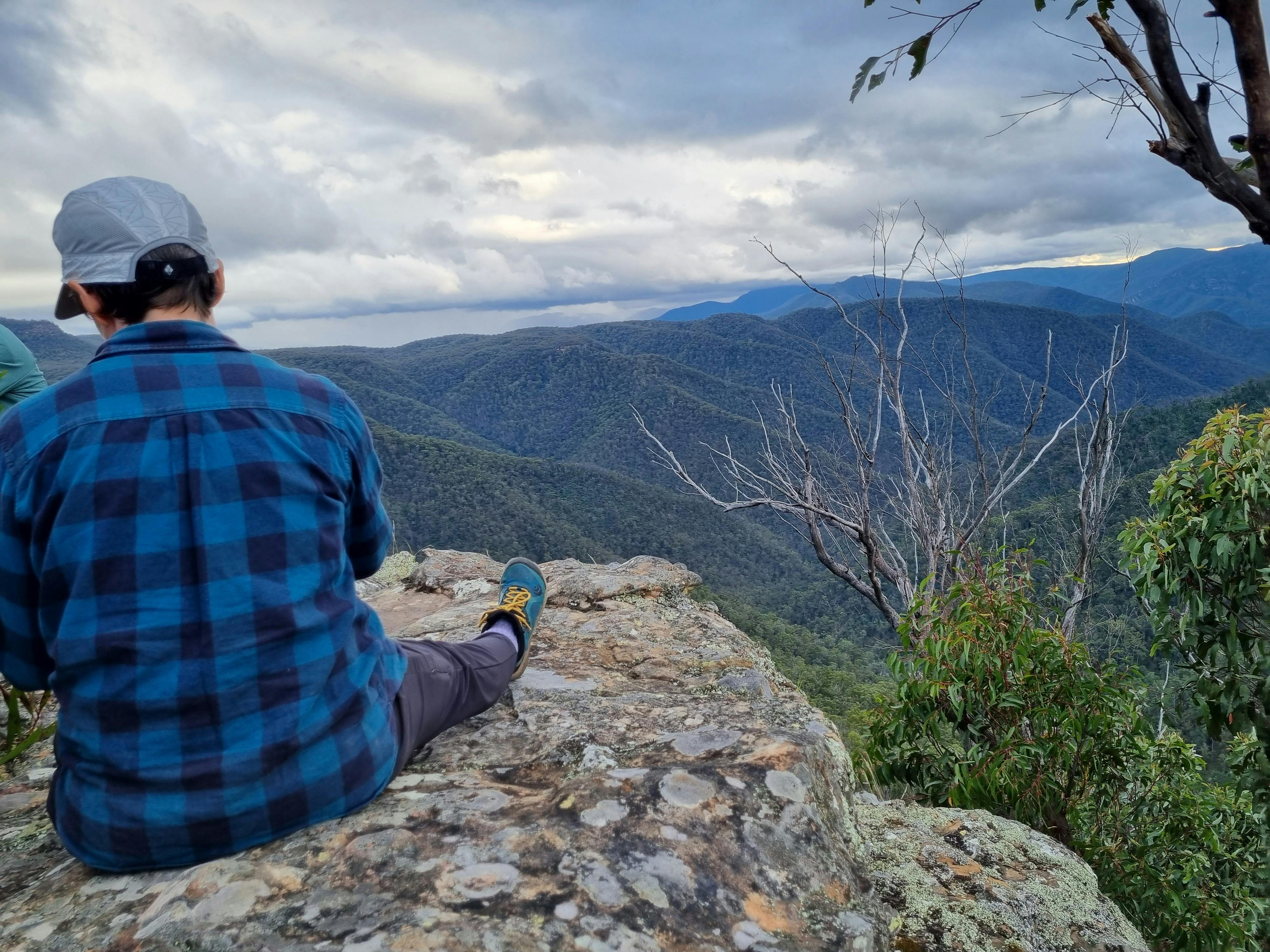 女性は荒野の尾根と峡谷を見下ろす展望台に座っています
