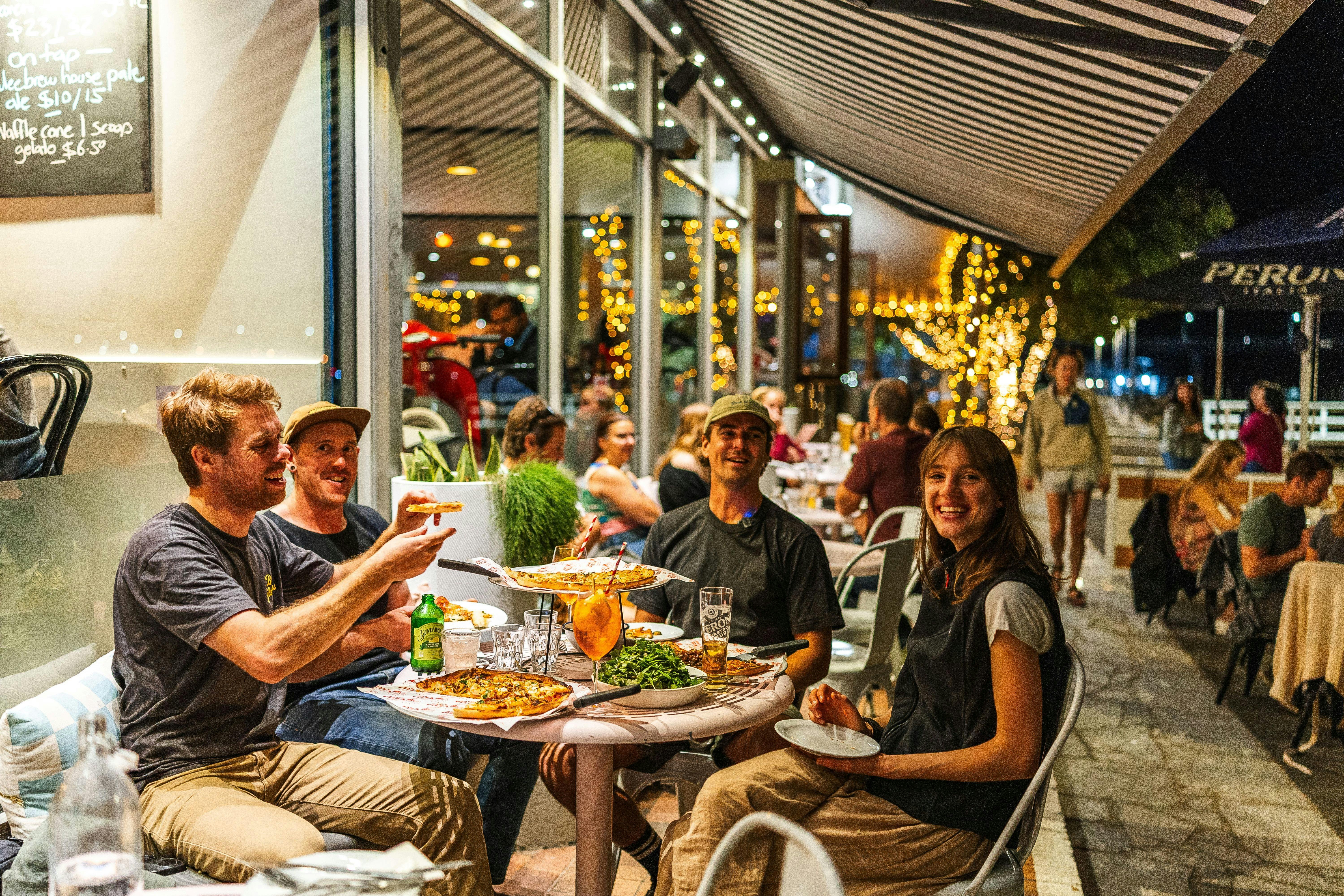 A group of friends sharing pizza at Sams Pizzeria