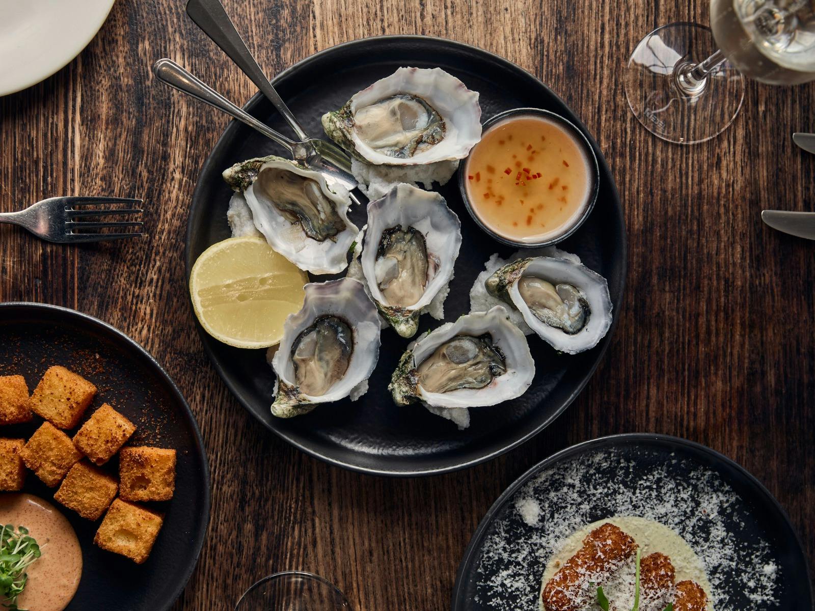 Picture of 6 natural oysters with a small plate of other snacks