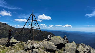Three hikers at the top of a mountain looking at the view.