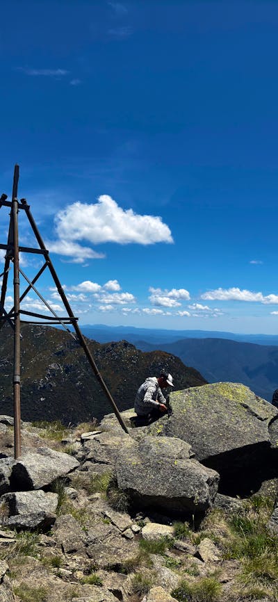 Three hikers at the top of a mountain looking at the view.