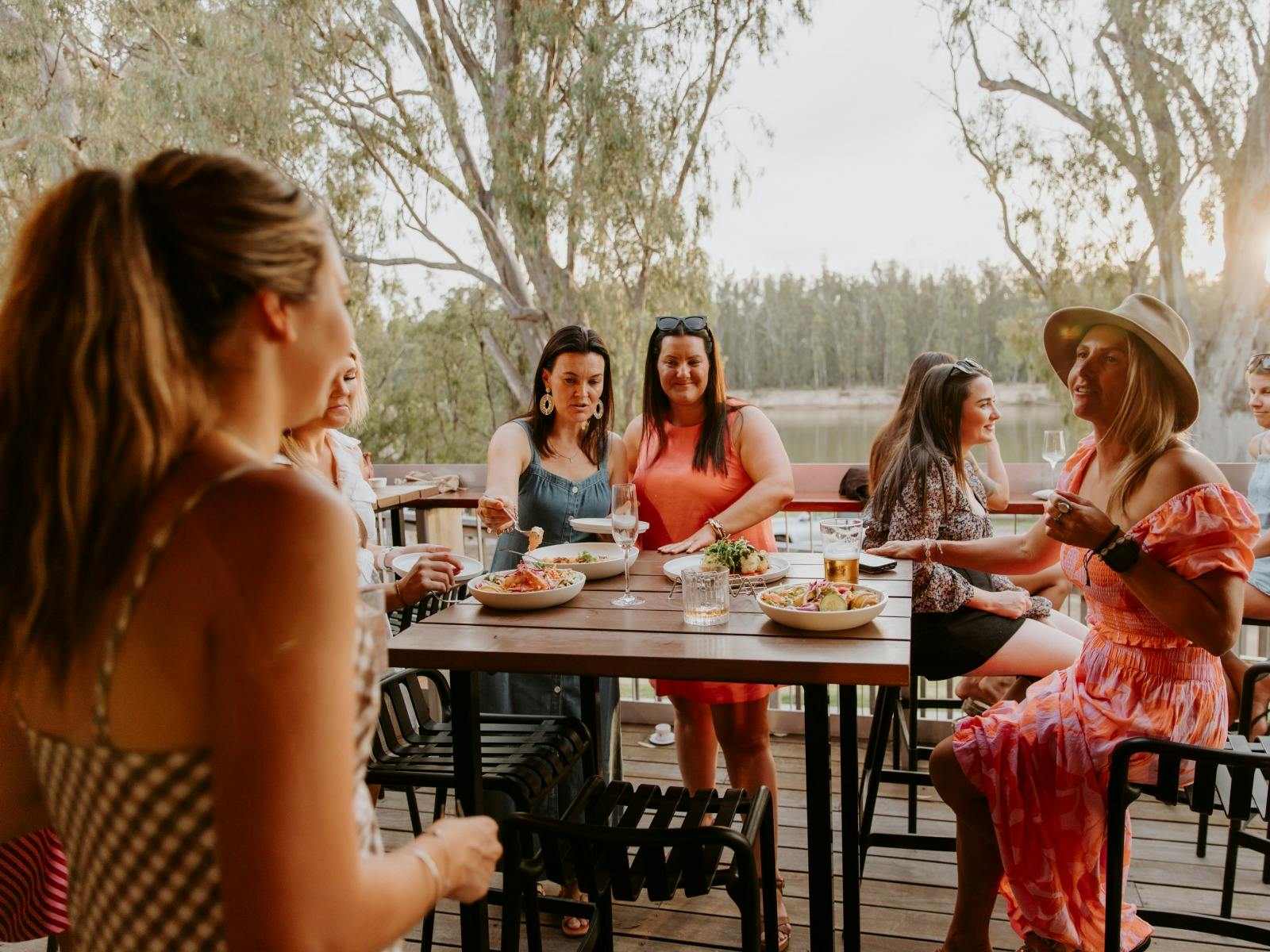 A group of women enjoying a meal on the deck at The Bend with Murray River Views
