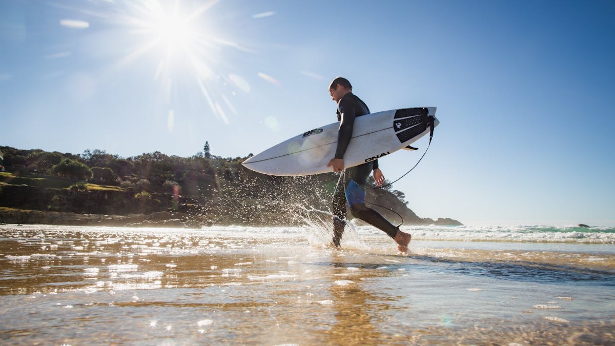 Smiling surfer walking along North Stradbroke Island beach after catching a wave