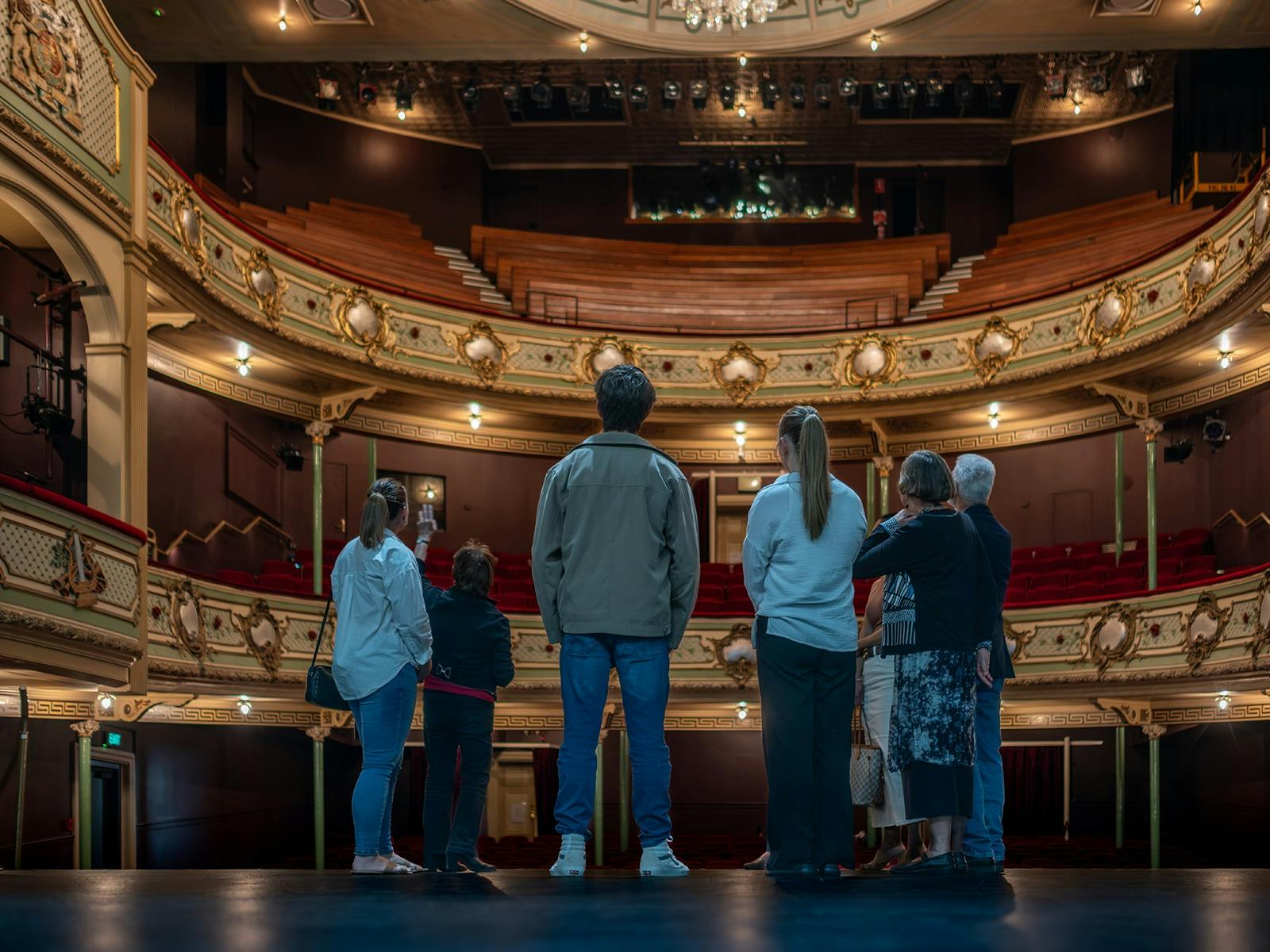 A group of people stand on the Theatre Royal stage looking around