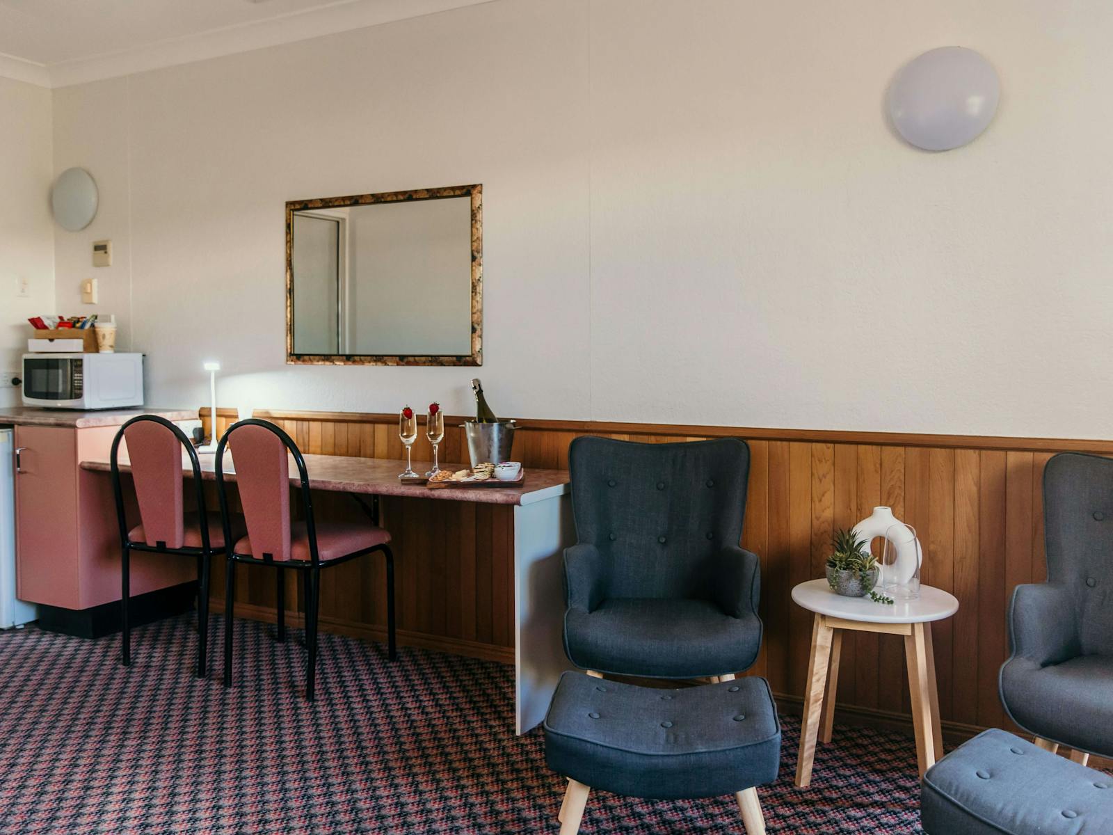 King Spa Room - A sitting area next to a desk with 2 chairs and a mounted wall mirror.