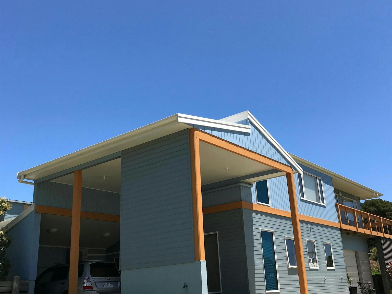 Clear blue sky in background with blue large beachhouse with orange accents