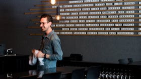 Staff member by the scrabble style menu on the wall