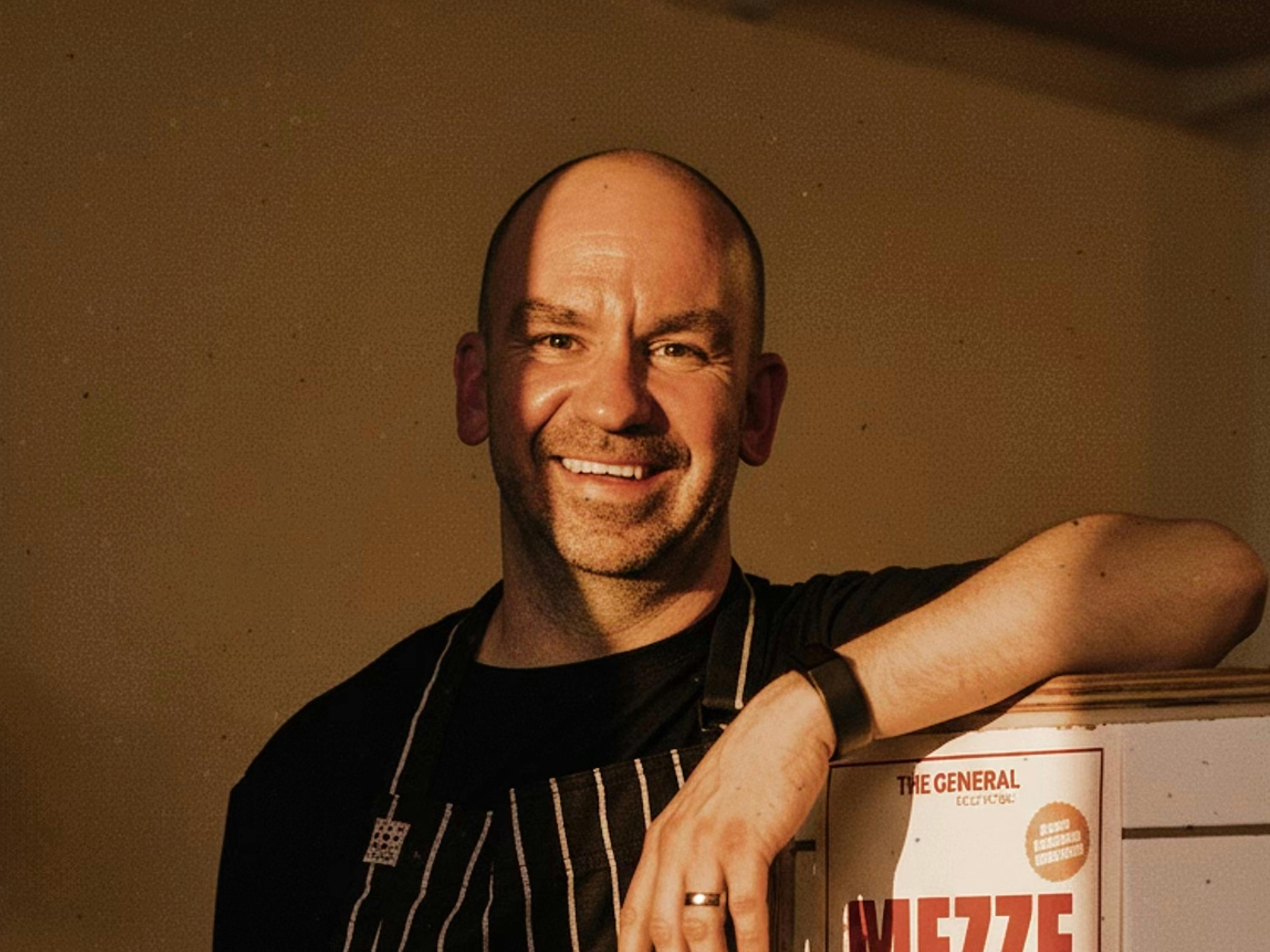 Owner and chef, Paul 'Dougie' Douglas standing in The General Food Store, smiling at the camera.