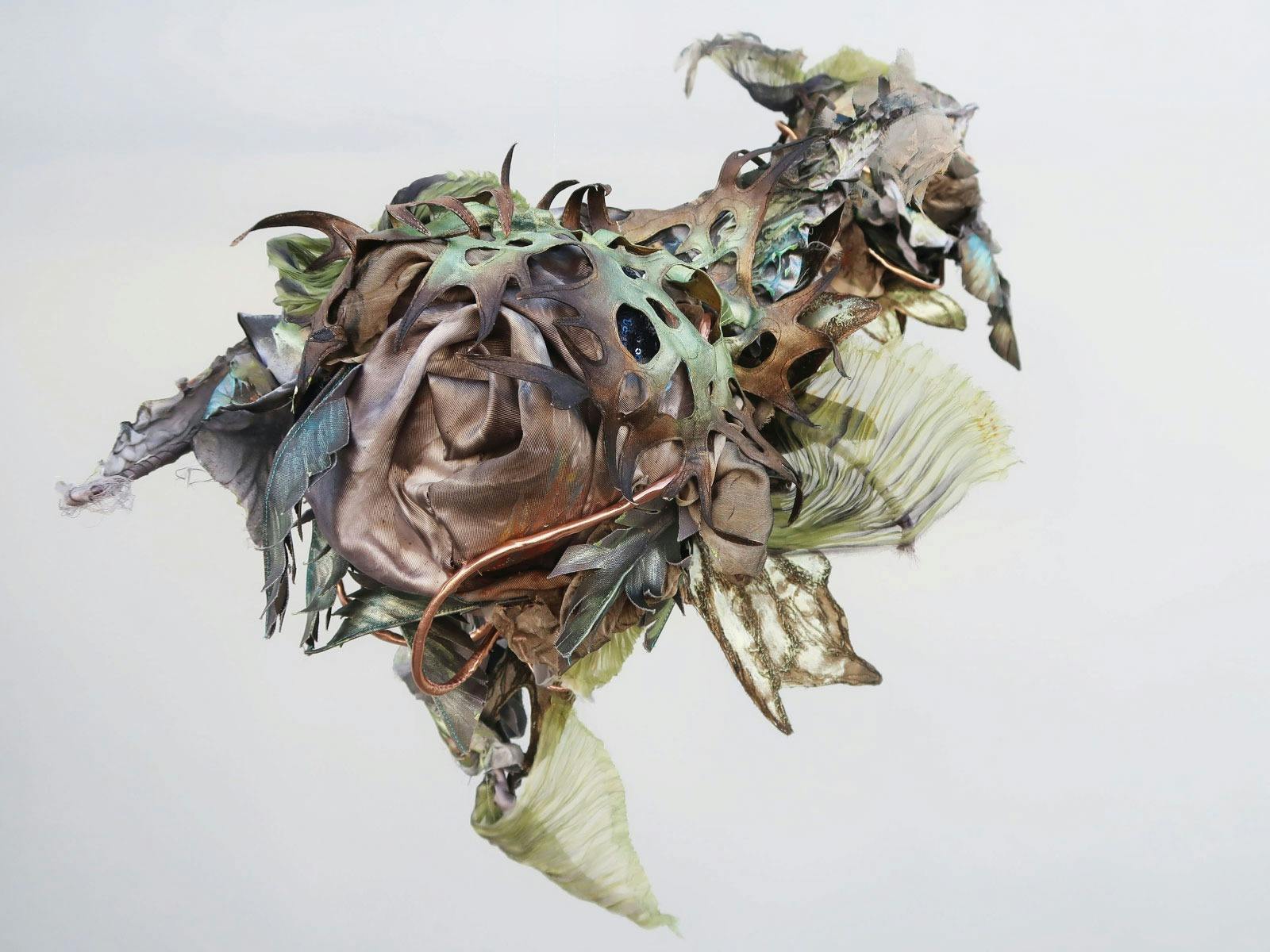 Close up mixed-media, 3D textile artwork  featuring blue, green and metallic bronze tones b