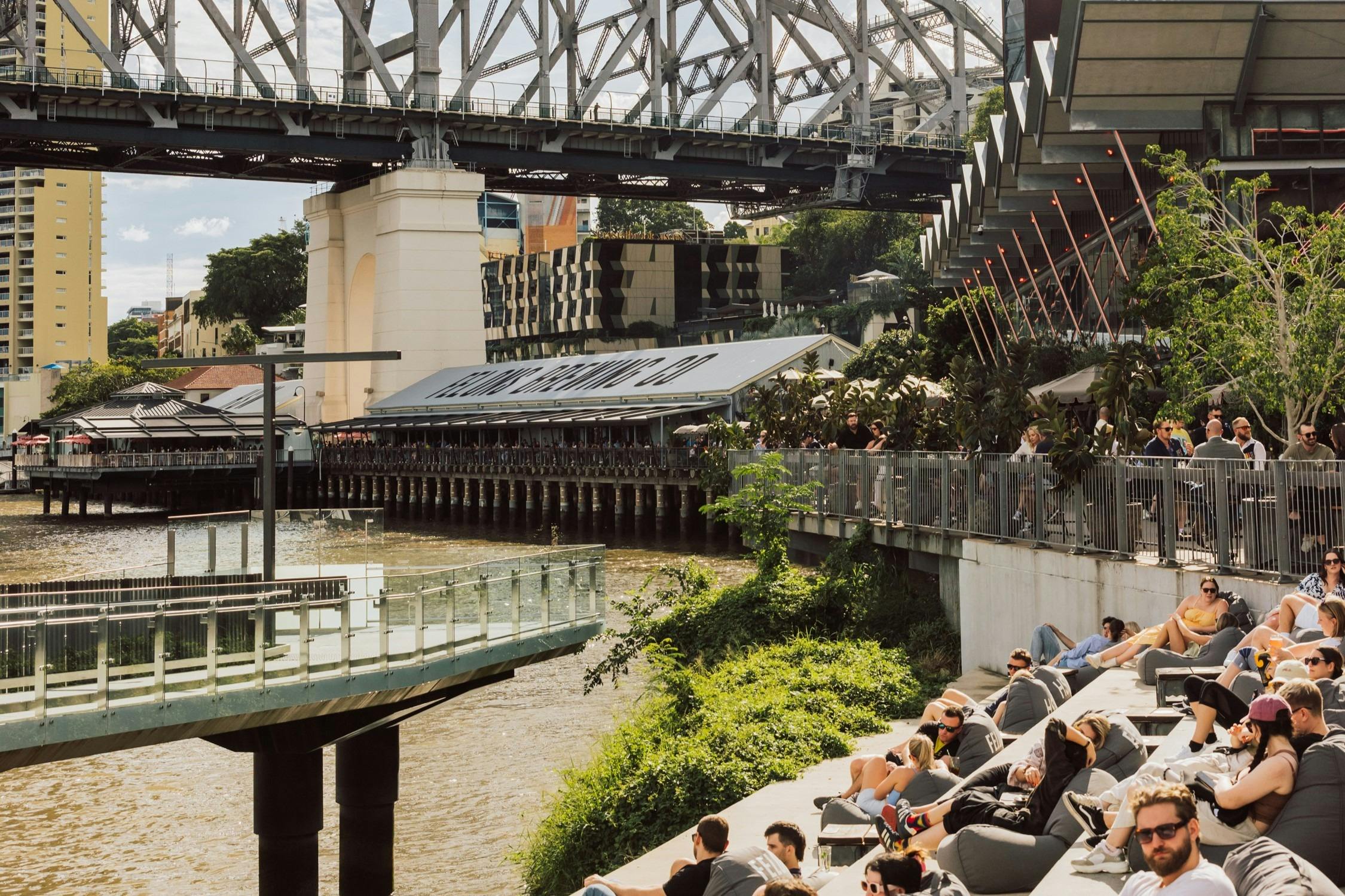 People sit by the river on bean bags outside Felons Barrel Hall