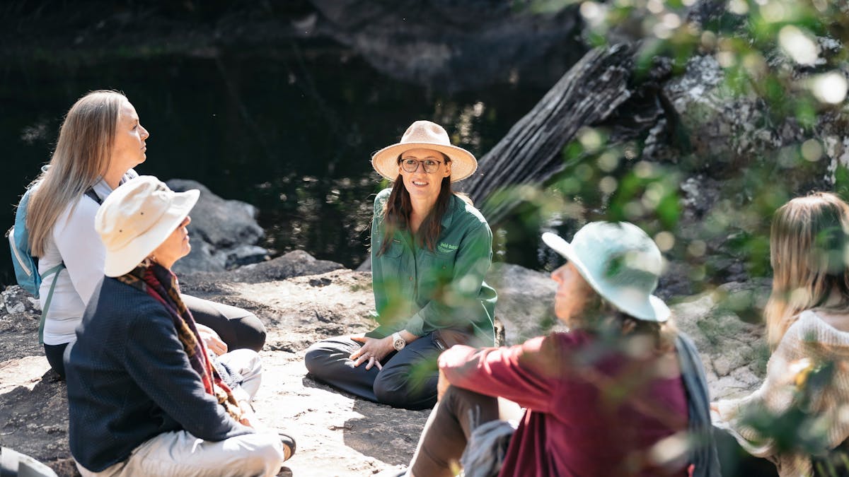 Circle of women sitting on rocks by a creek