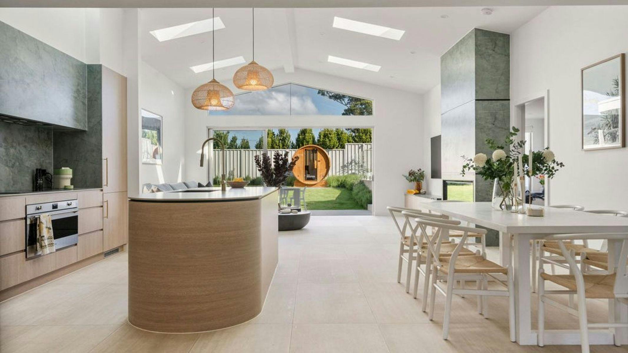 Image of interior, view from kitchen to outdoor space and lounge area. Soft lighe spacet fills th