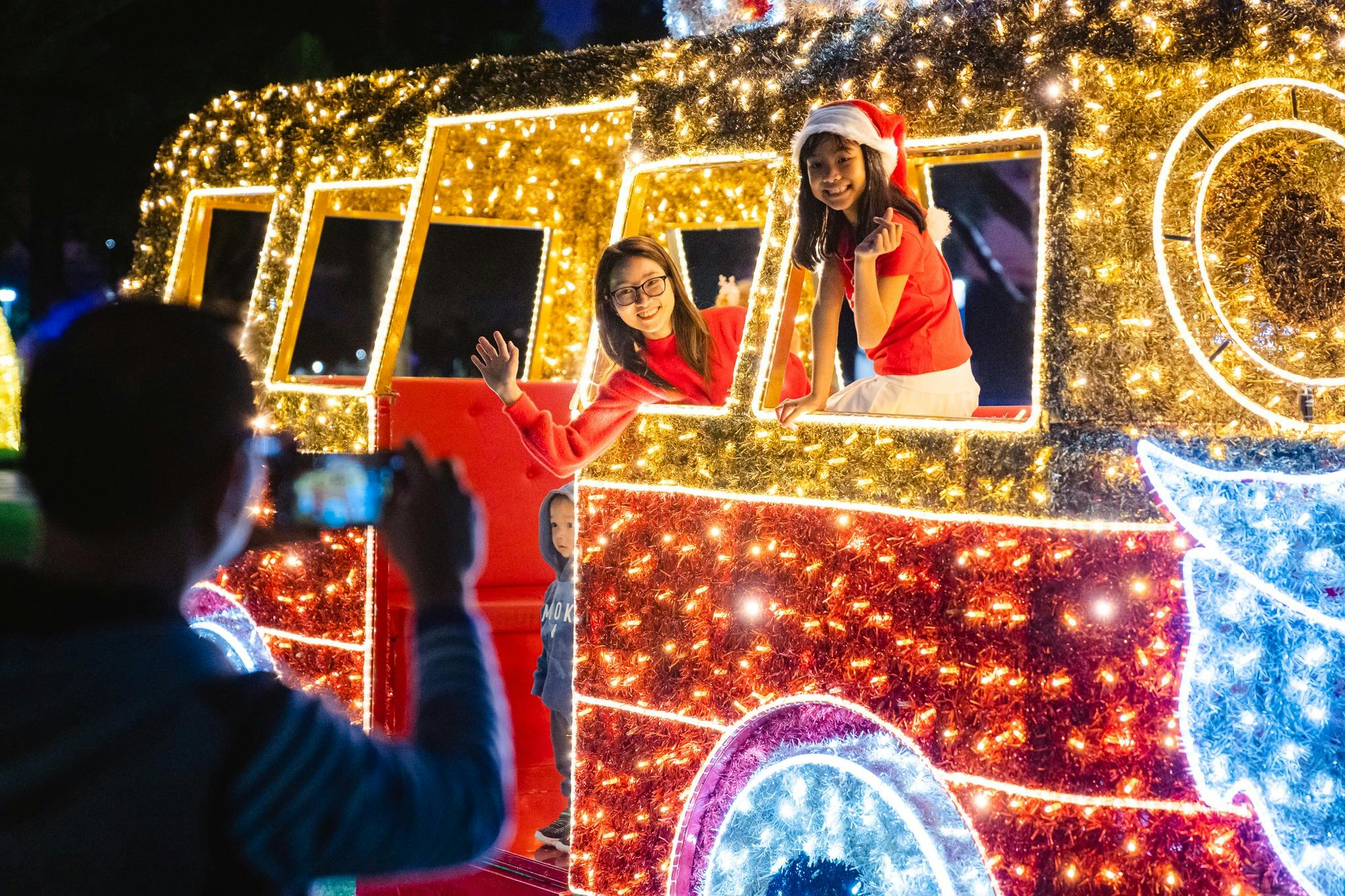 Visitors pose in a glowing Christmas train light display during festive celebrations in Mandurah.