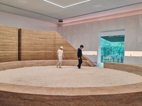 Two visitors stand in the middle ofn a circular stone art installation with sand in the middle