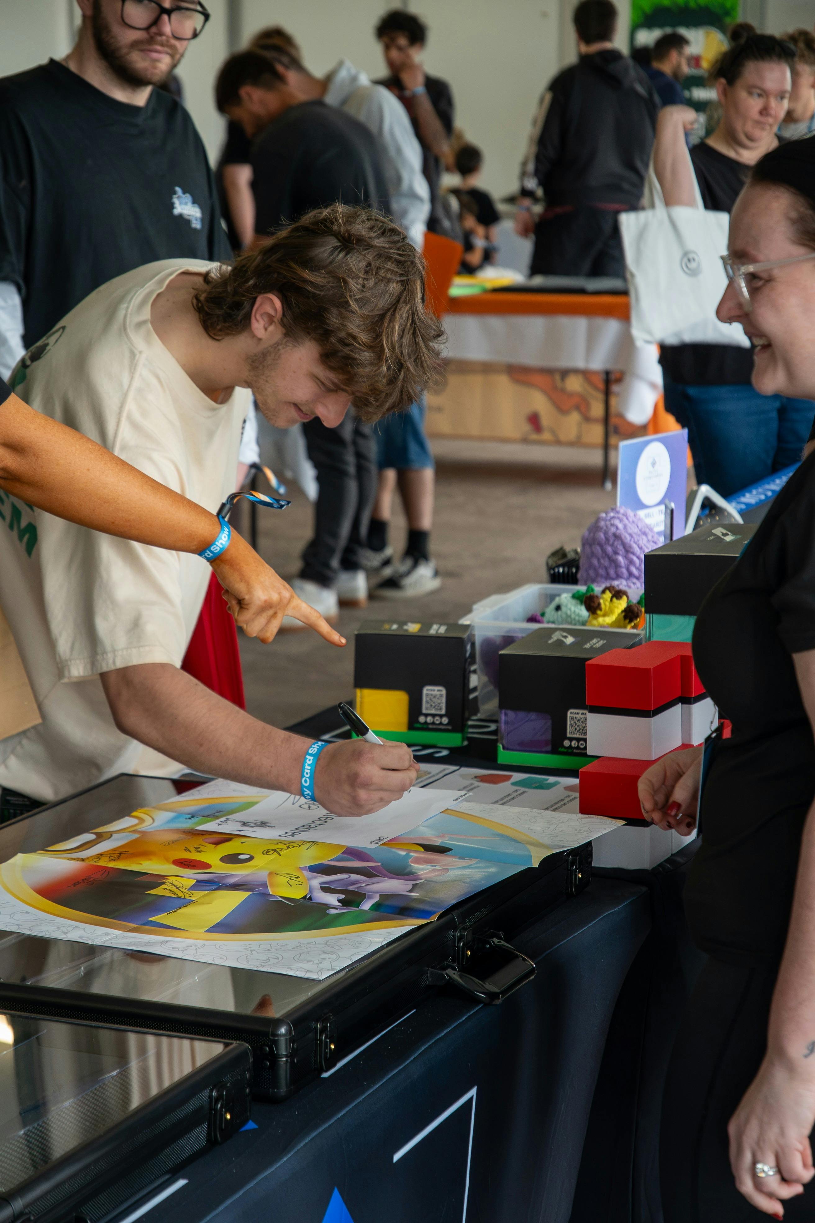 A man signs a Pokémon poster