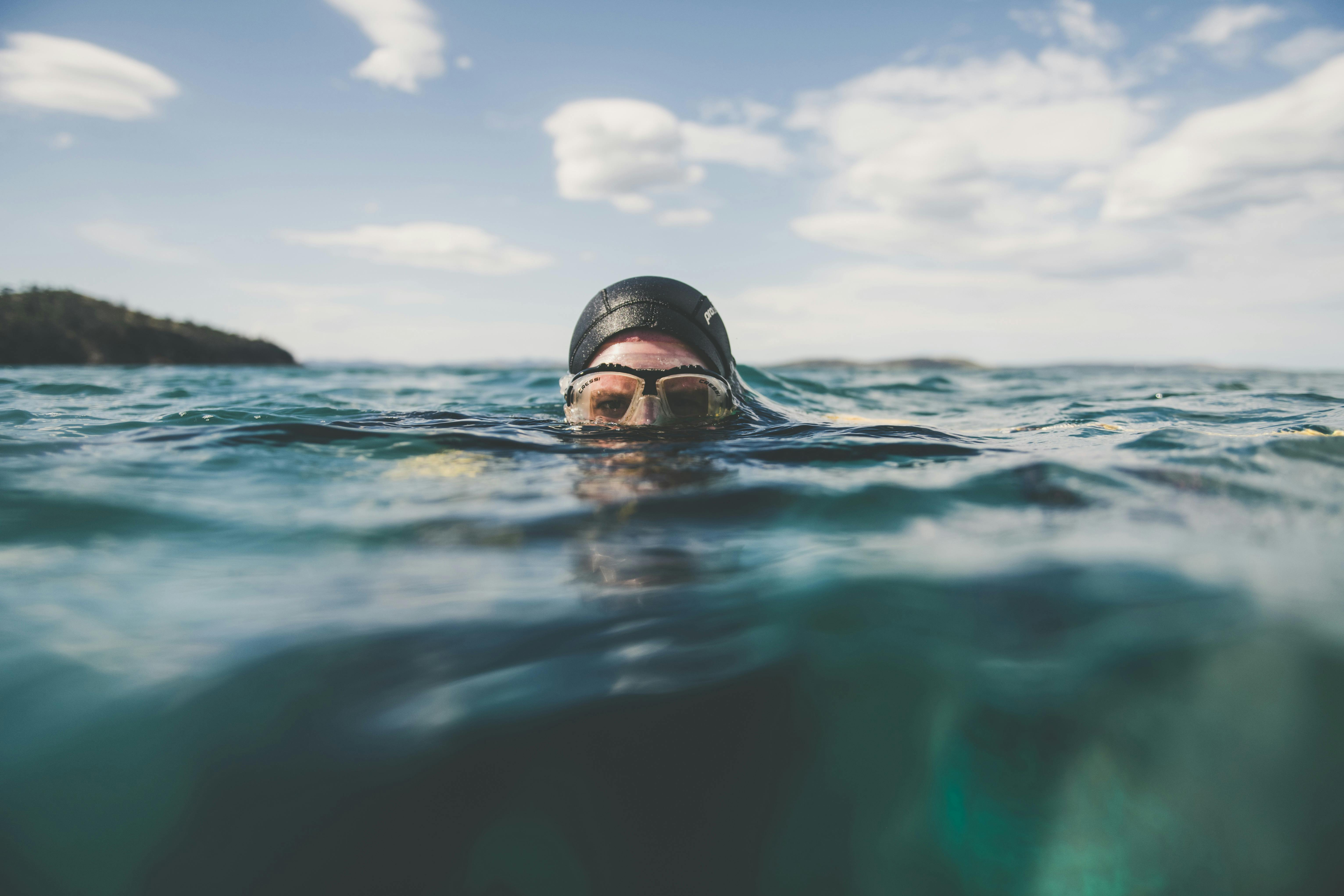 A diver is in the water with only their eyes above the waterline
