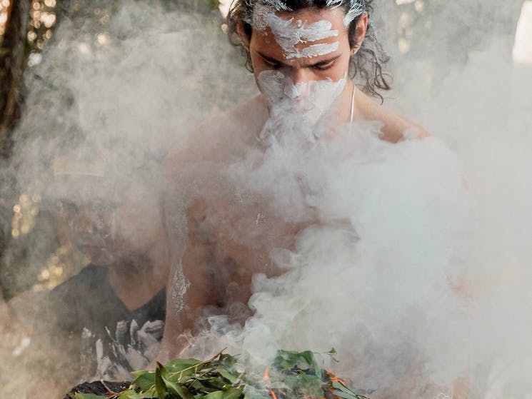 Indigenous Man holding fire in a wooden bowl in order to perform the Smoking Ceremony with guests
