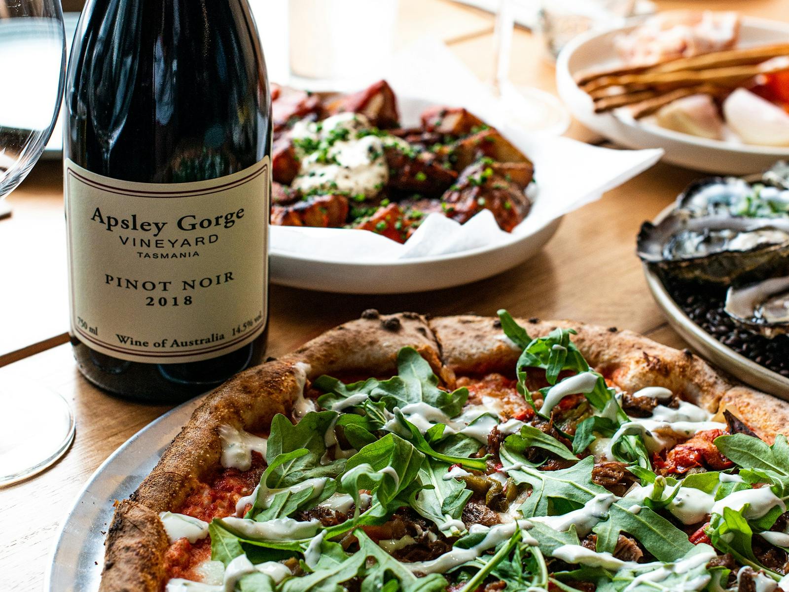 A delicious looking pizza and a bottle of red wine