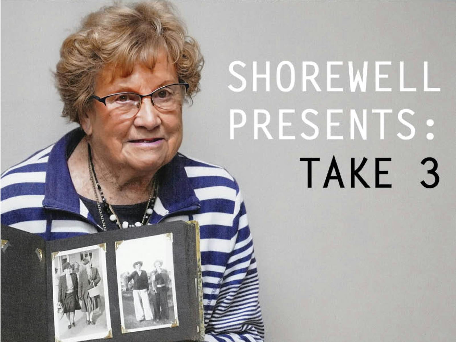 Older lady with glasses  in blue and white top holding photo album
