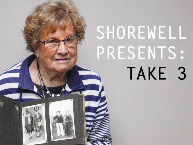 Older lady with glasses  in blue and white top holding photo album
