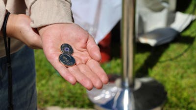 a hand holding 2 traded coins at the Mint