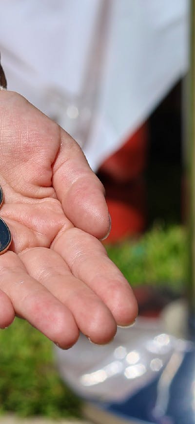 a hand holding 2 traded coins at the Mint