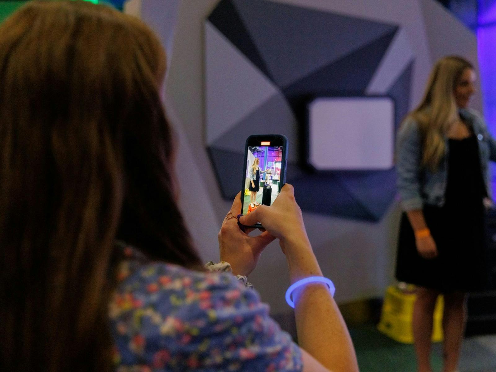 A woman taking a photo of her friend at Questacon After Dark