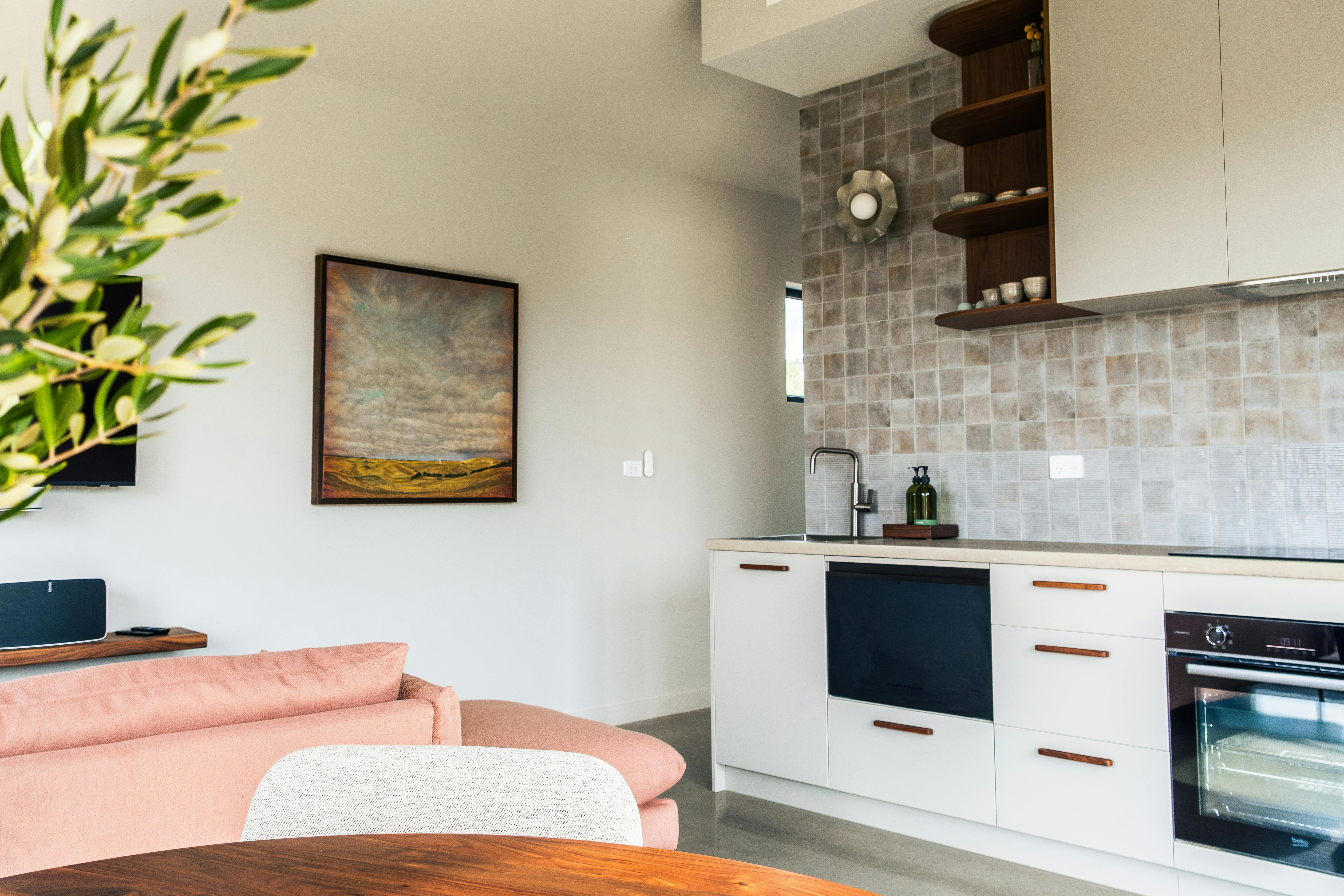 a kitchen area, a large painting is on the wall and you can just see a dining table and couch