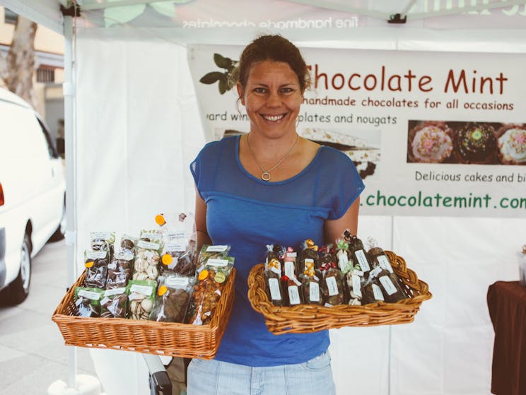 Stallholder from Chocolate mint is holding baskets of handmade chocolates and sweets