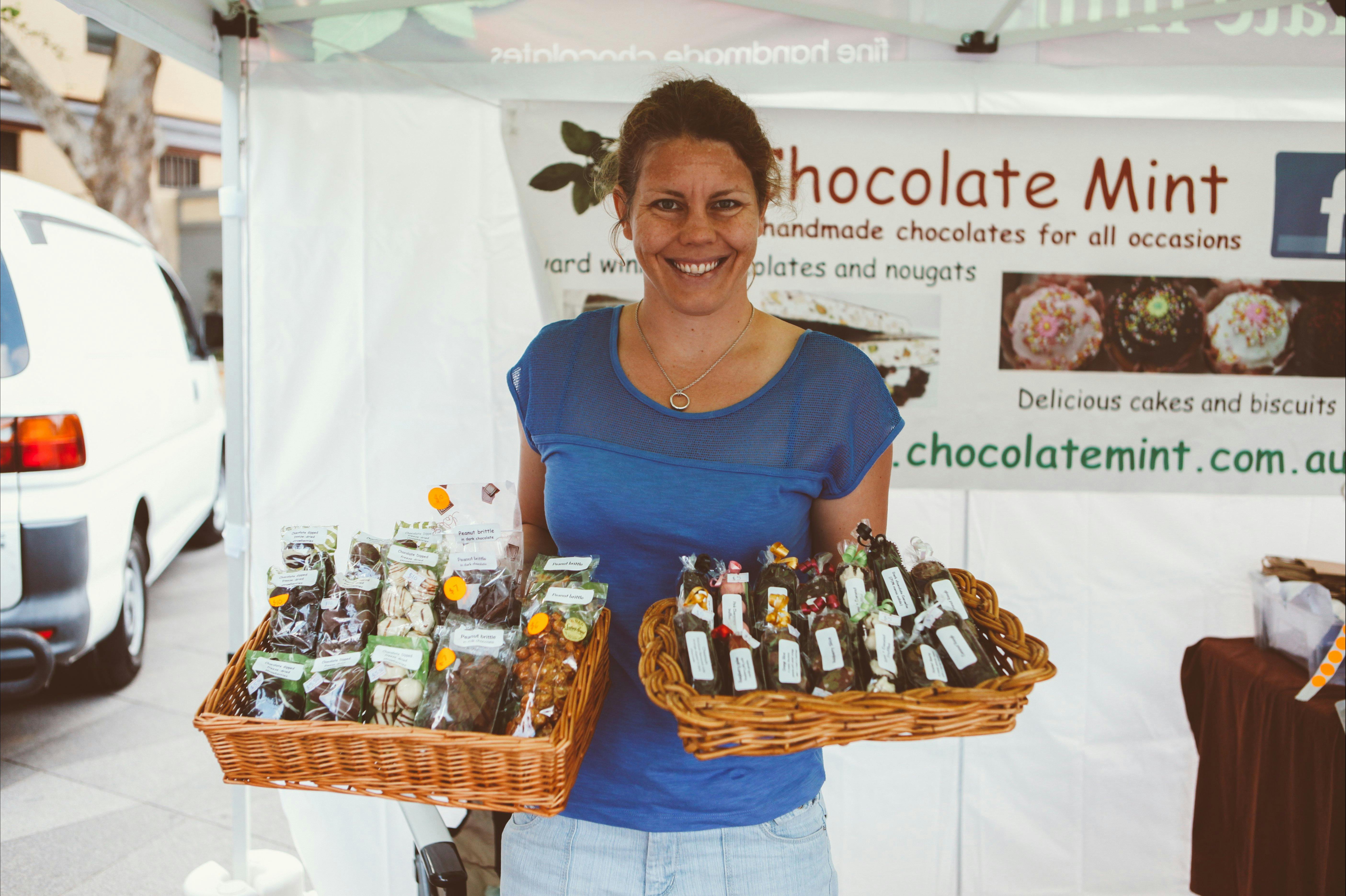 Stallholder from Chocolate mint is holding baskets of handmade chocolates and sweets