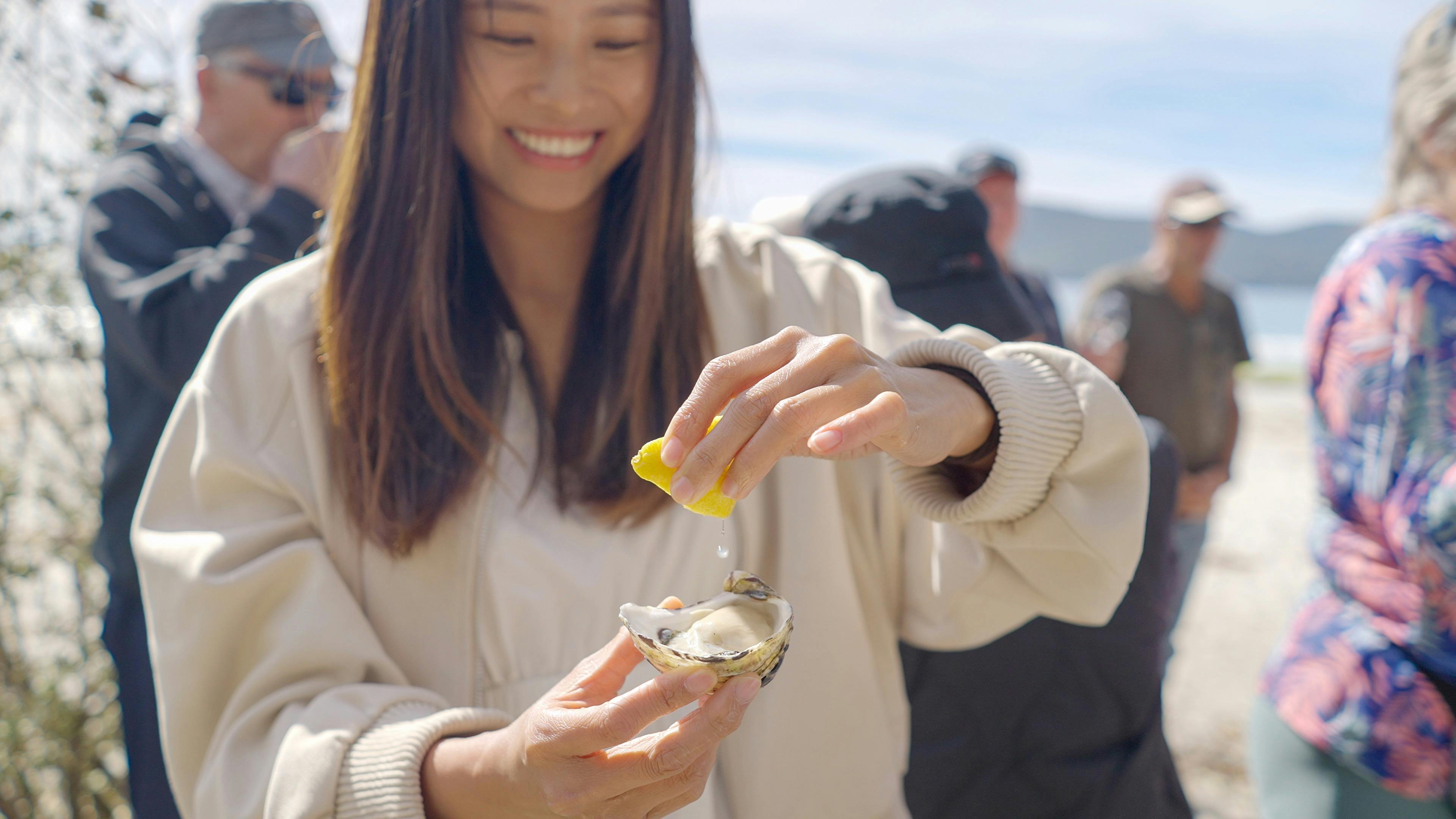 Guest tasting a freshly shucked oysters by the beach