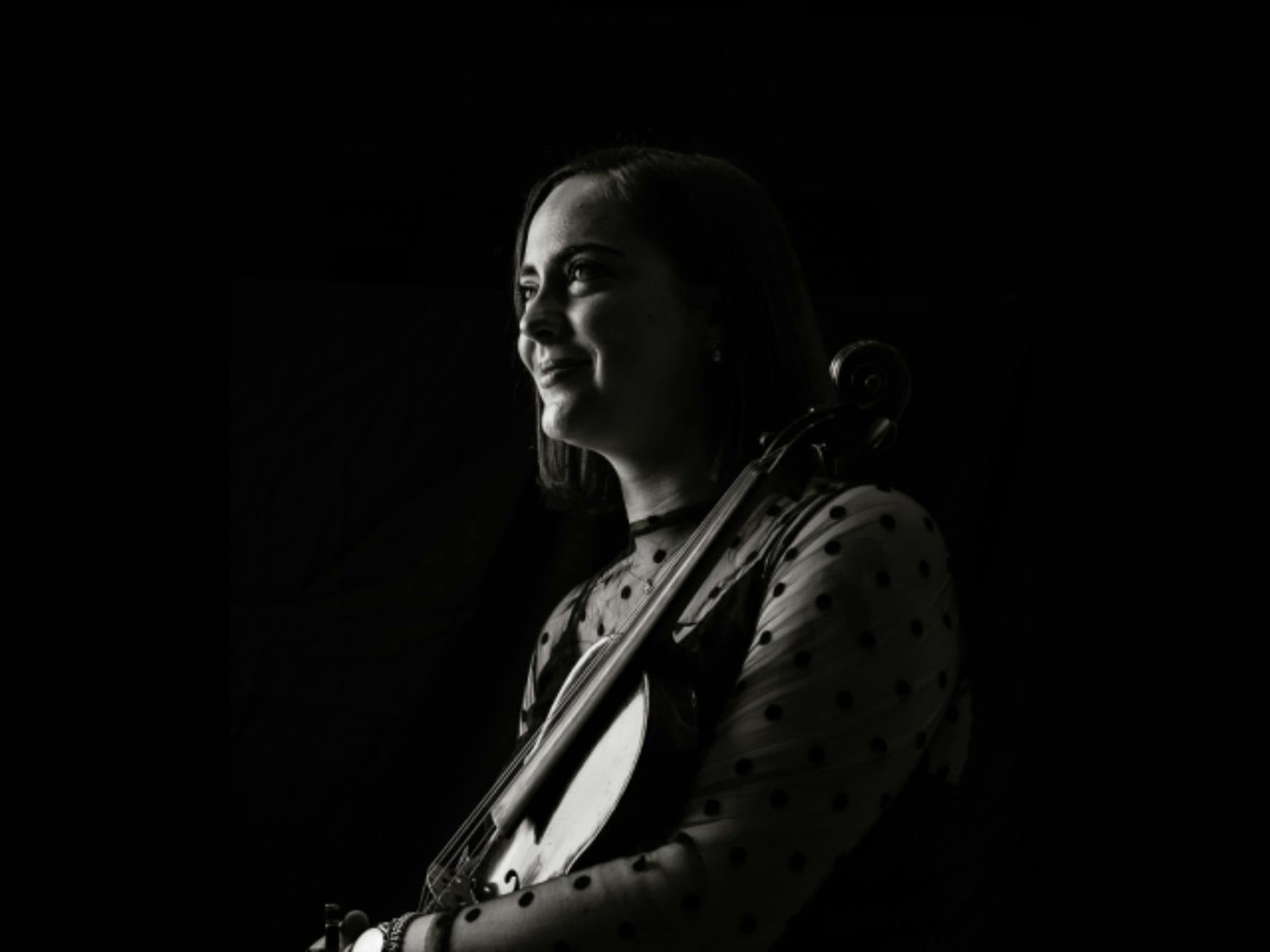 Black-and-white portrait of a violinist in profile, looking toward the light
