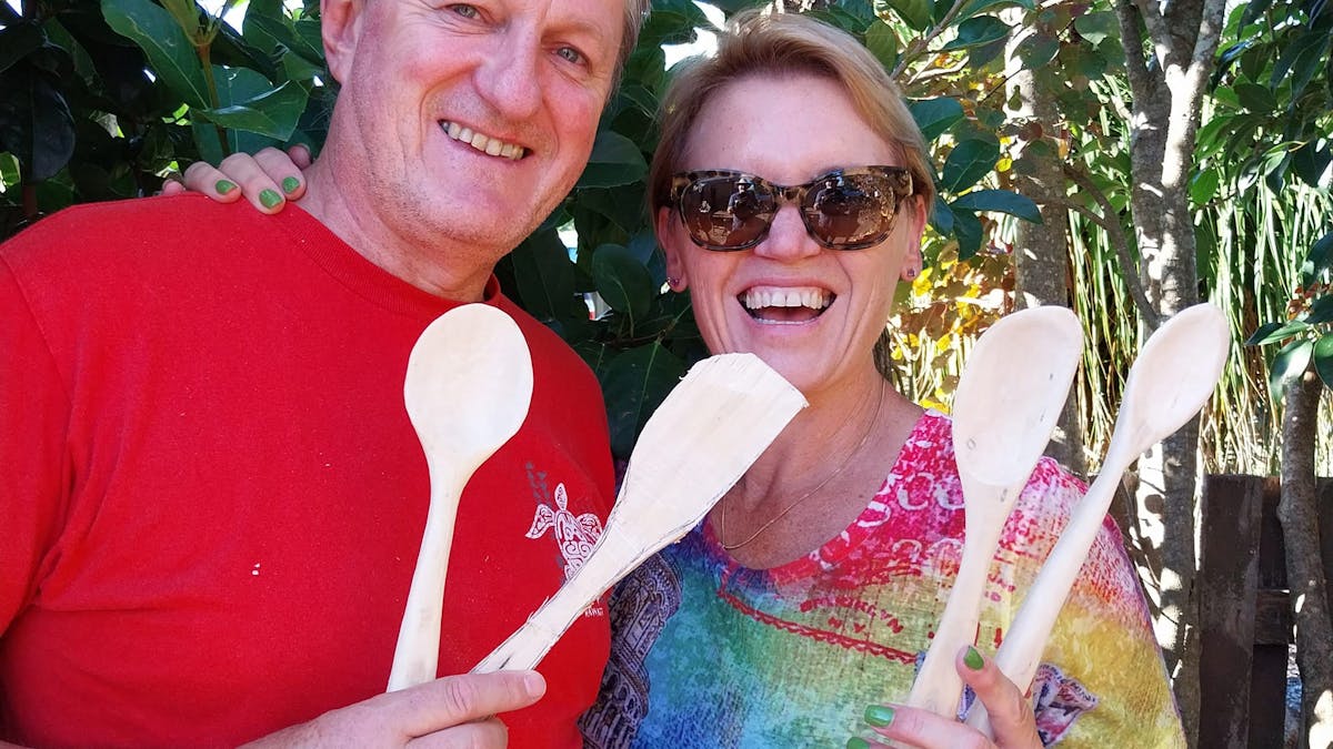 2 smiling people holding wooden spoons