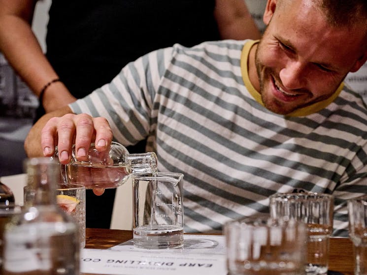 A smiling young man carefully pours liquid from a bottle to a beaker